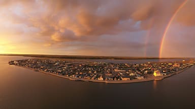 An aerial view of a coastal town with a rainbow over the water.