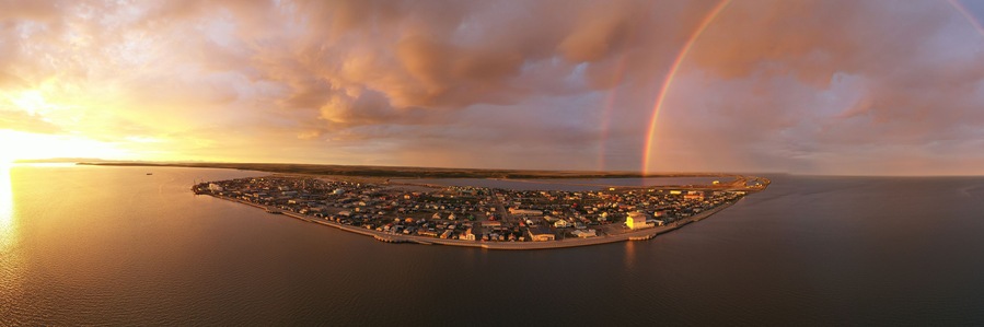 An aerial view of a coastal town with a rainbow over the water.