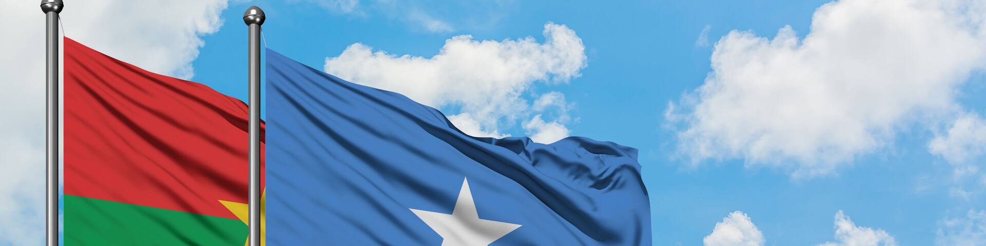 Burkina Faso and Somalia flag waving in the wind against white cloudy blue sky together. Diplomacy concept, international relations.