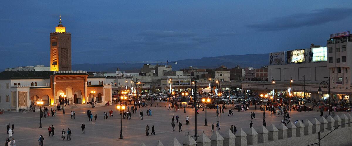 A bustling square with a prominent tower and a mosque with a minaret.