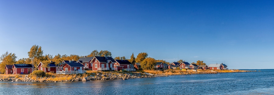 idyllic Baltic Sea panorama landscape with red cottages on the shoreline under a blue sky in autumn
