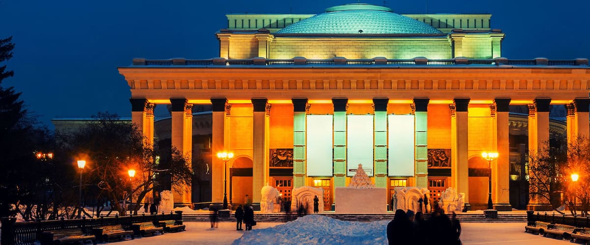 A grand building with a dome and columns, illuminated at night.