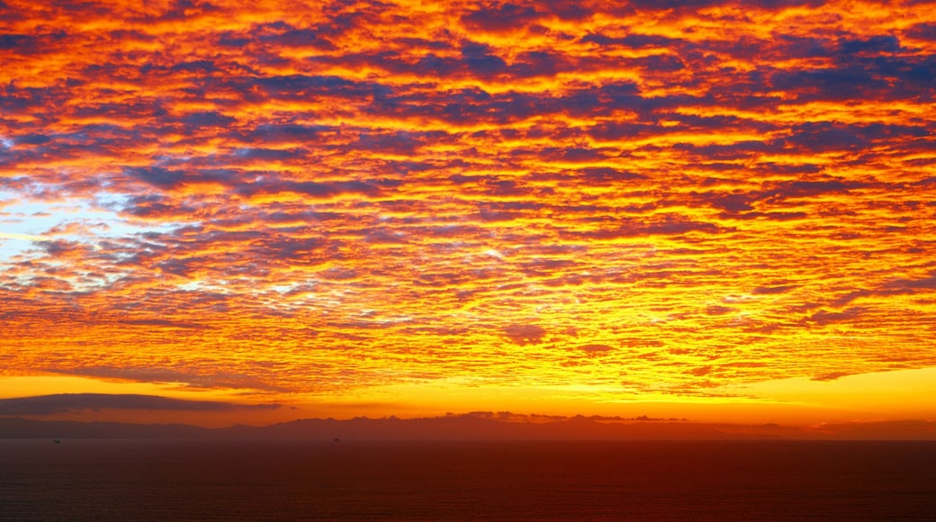 Un atardecer sobre el océano con nubes vibrantes de color naranja y rojo.