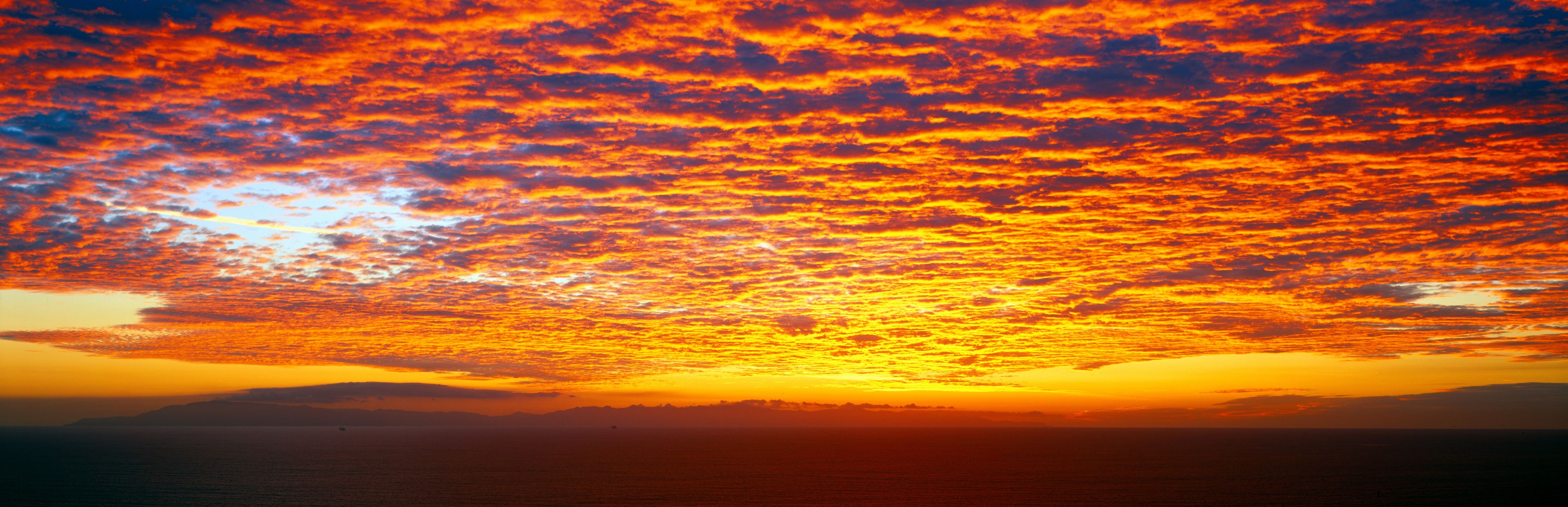 A sunset over the ocean with vibrant orange and red clouds.