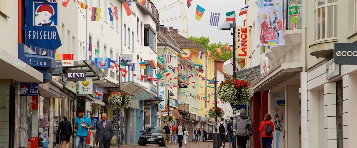 A pedestrian street lined with shops and decorated with international flags.