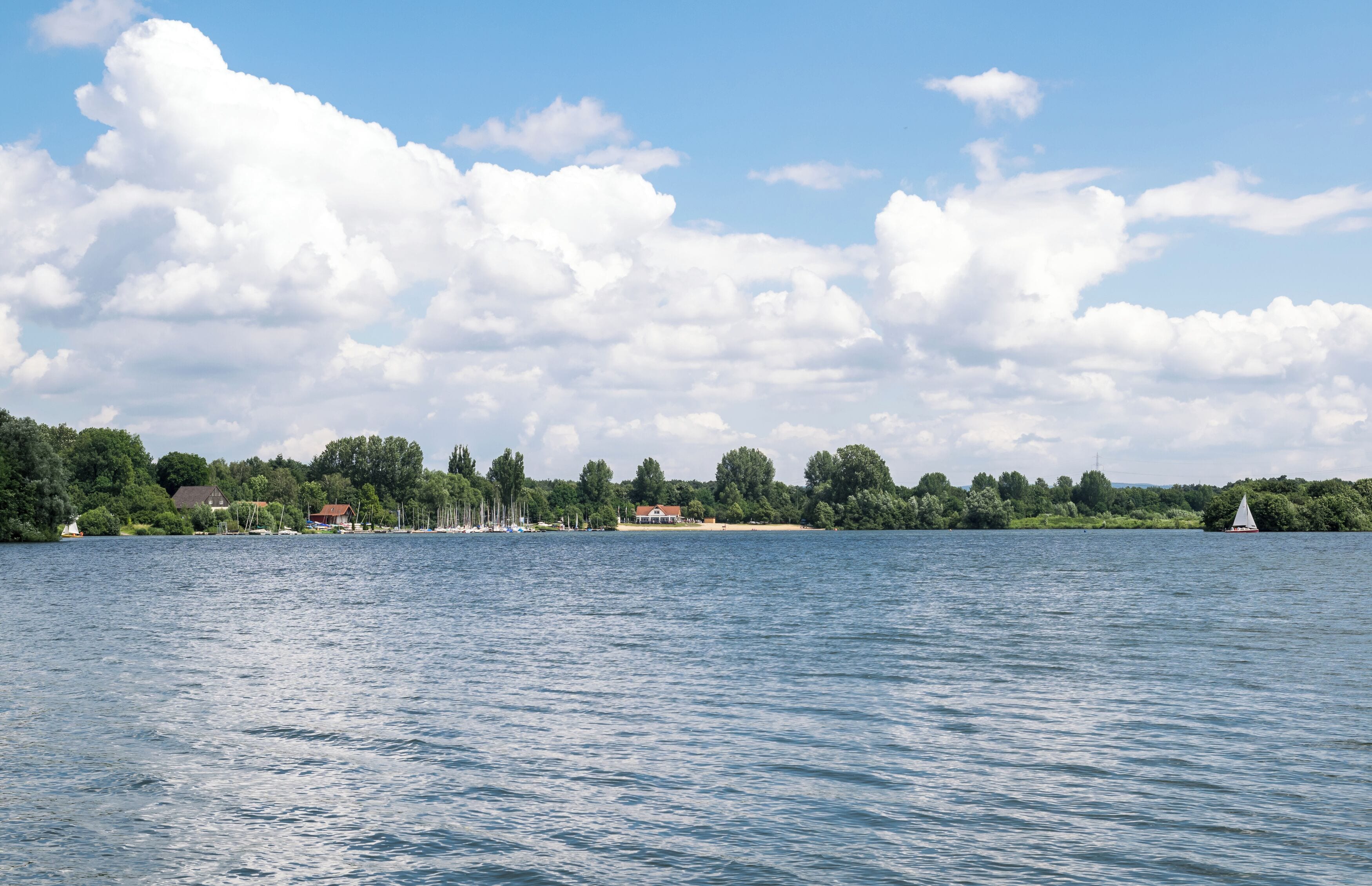 A lake with a row of houses and trees on the shore.