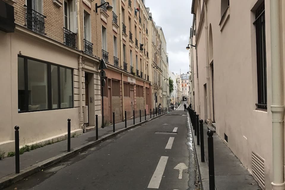 Eine schmale Stadtstraße, gesäumt von mehrstöckigen Gebäuden mit Balkonen und Fenstern.