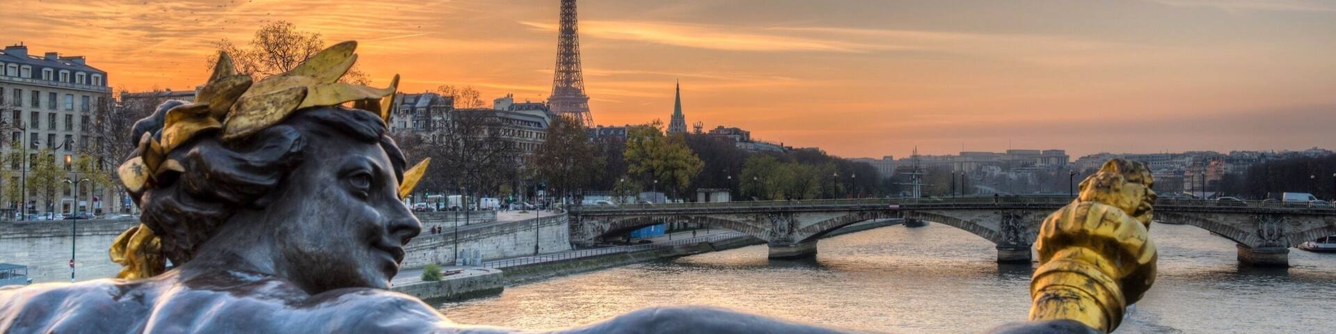 A statue of a figure with a laurel wreath, a bridge, and the Eiffel Tower in the background.