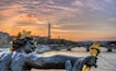 Une statue représentant une figure couronnée d’une couronne de laurier, avec un pont et la Tour Eiffel en arrière-plan.