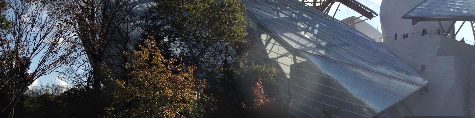 Un edificio de arquitectura moderna con fachada de vidrio curvo y estructura metálica.