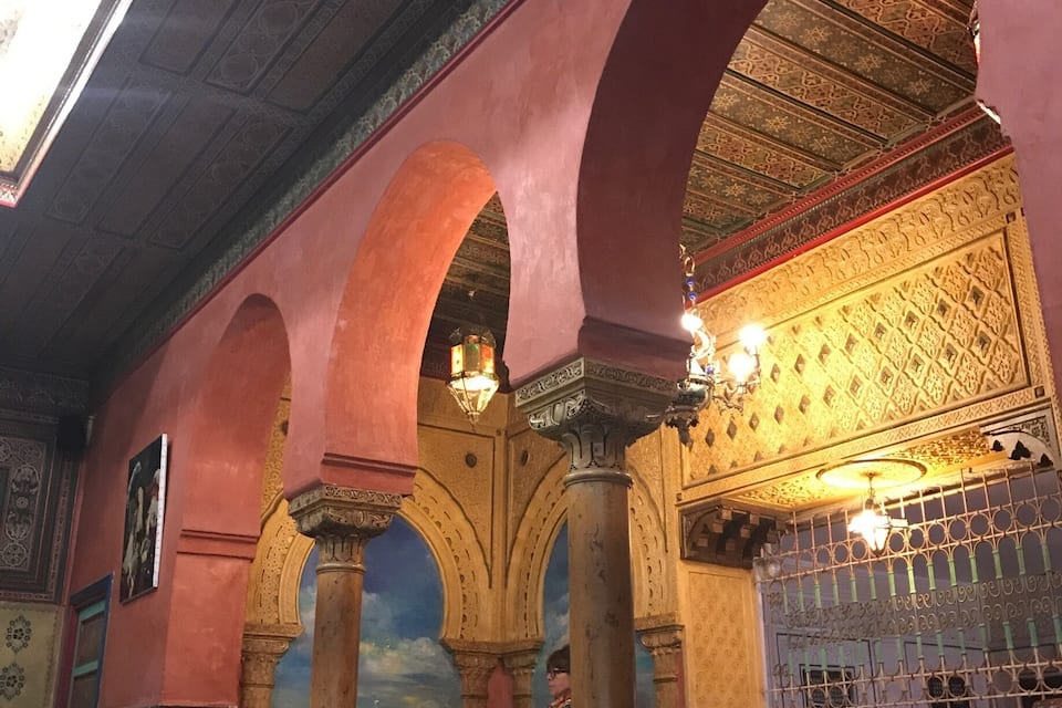 Un intérieur caractérisé par des arches, des colonnes et des motifs décoratifs complexes au plafond.