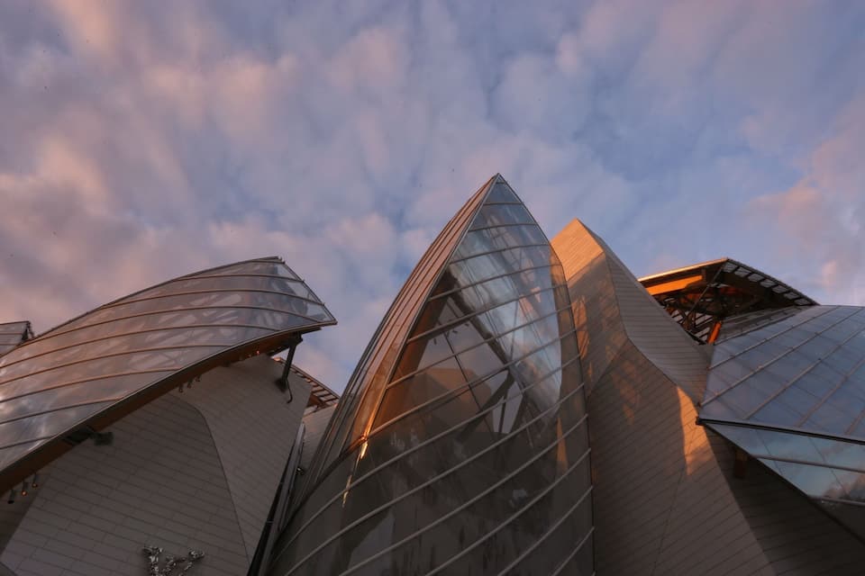 A modern architectural structure with reflective glass surfaces and angular shapes.