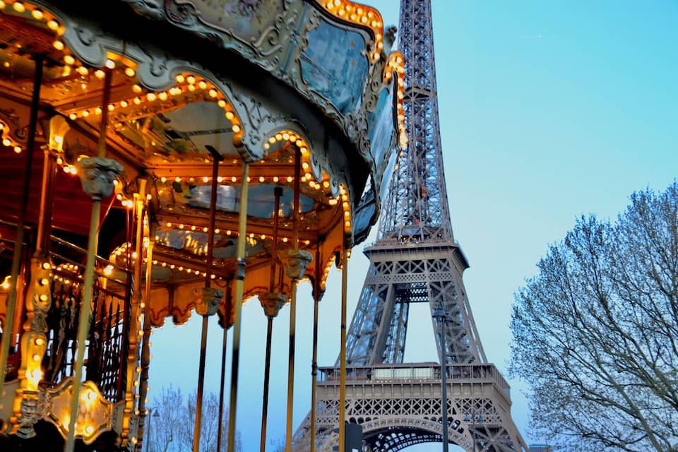 A carousel with lights and the Eiffel Tower in the background.