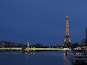The Eiffel Tower at dusk with a bridge and boats in the foreground.