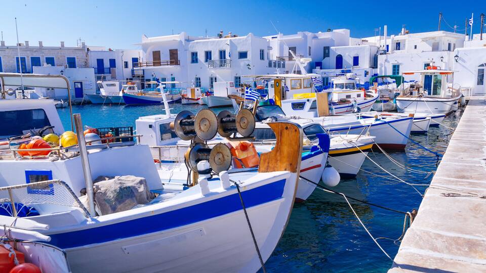 A marina with several boats docked, surrounded by white buildings with blue accents.