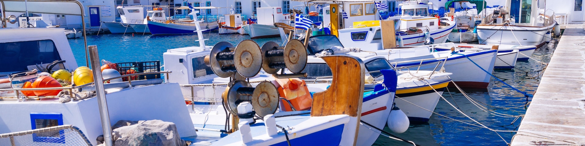 A marina with several boats docked, surrounded by white buildings with blue accents.