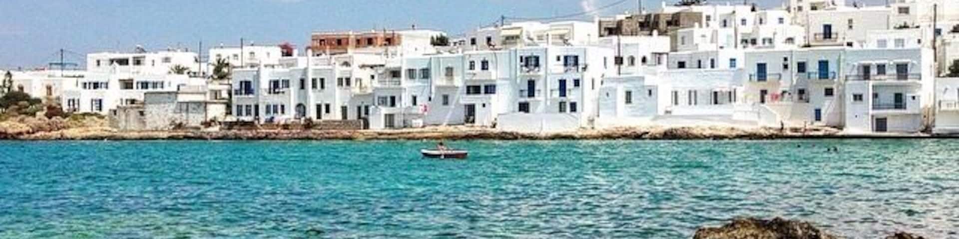 Un pueblo costero con edificios blancos, agua azul cristalina y costa rocosa.