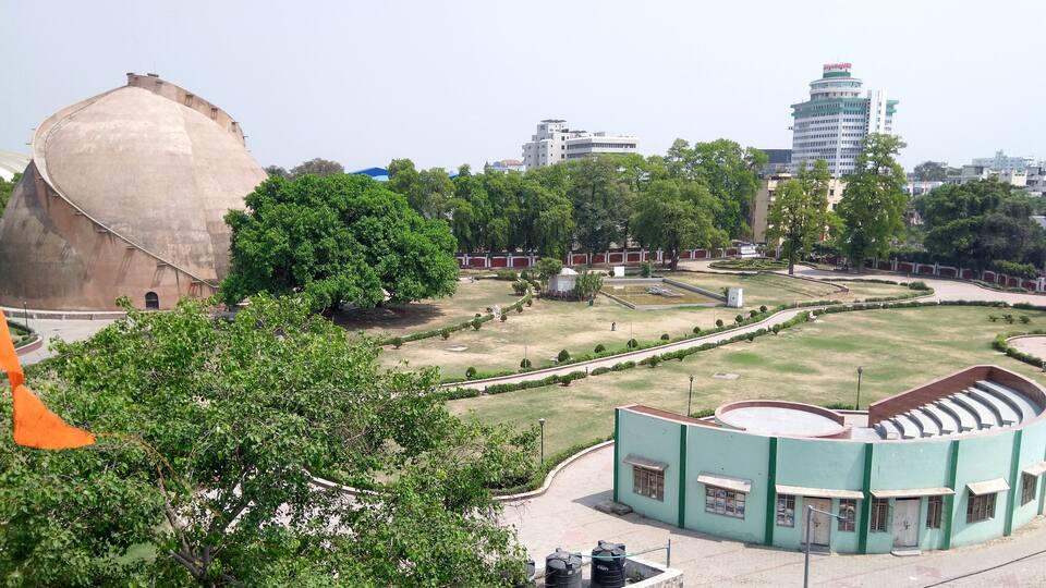 A large dome structure, a green building with a curved roof, and a tall building in the background.