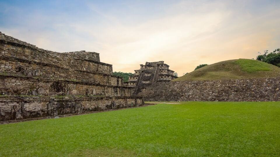 Ancient stone ruins with a grassy field and a hill in the background.