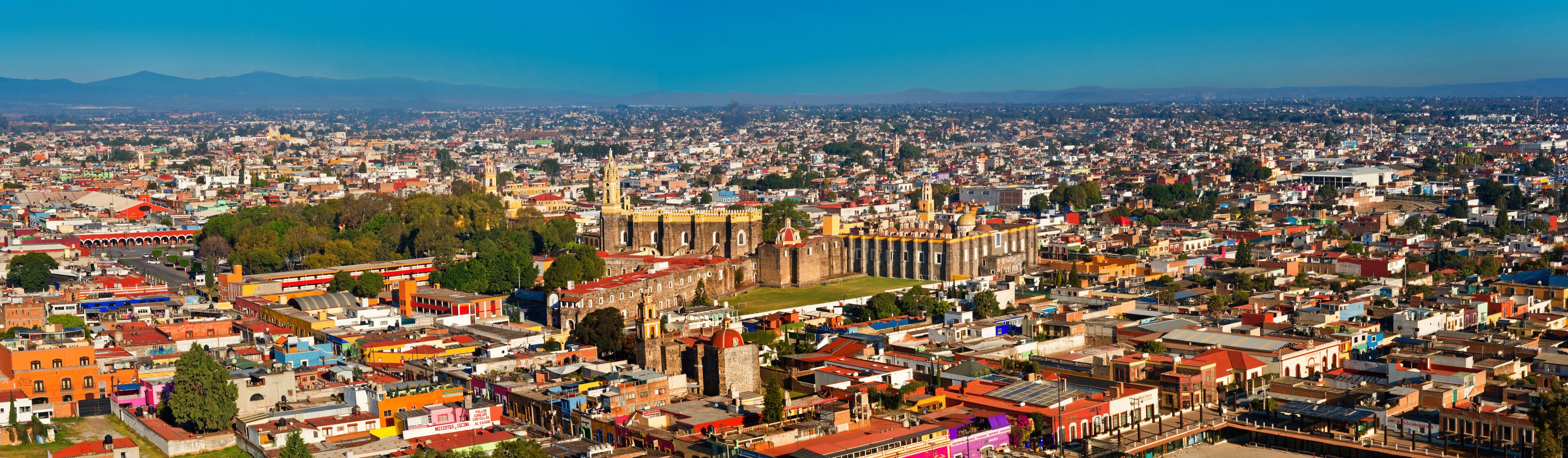 A panoramic view of a city with a prominent cathedral and surrounding colorful buildings.
