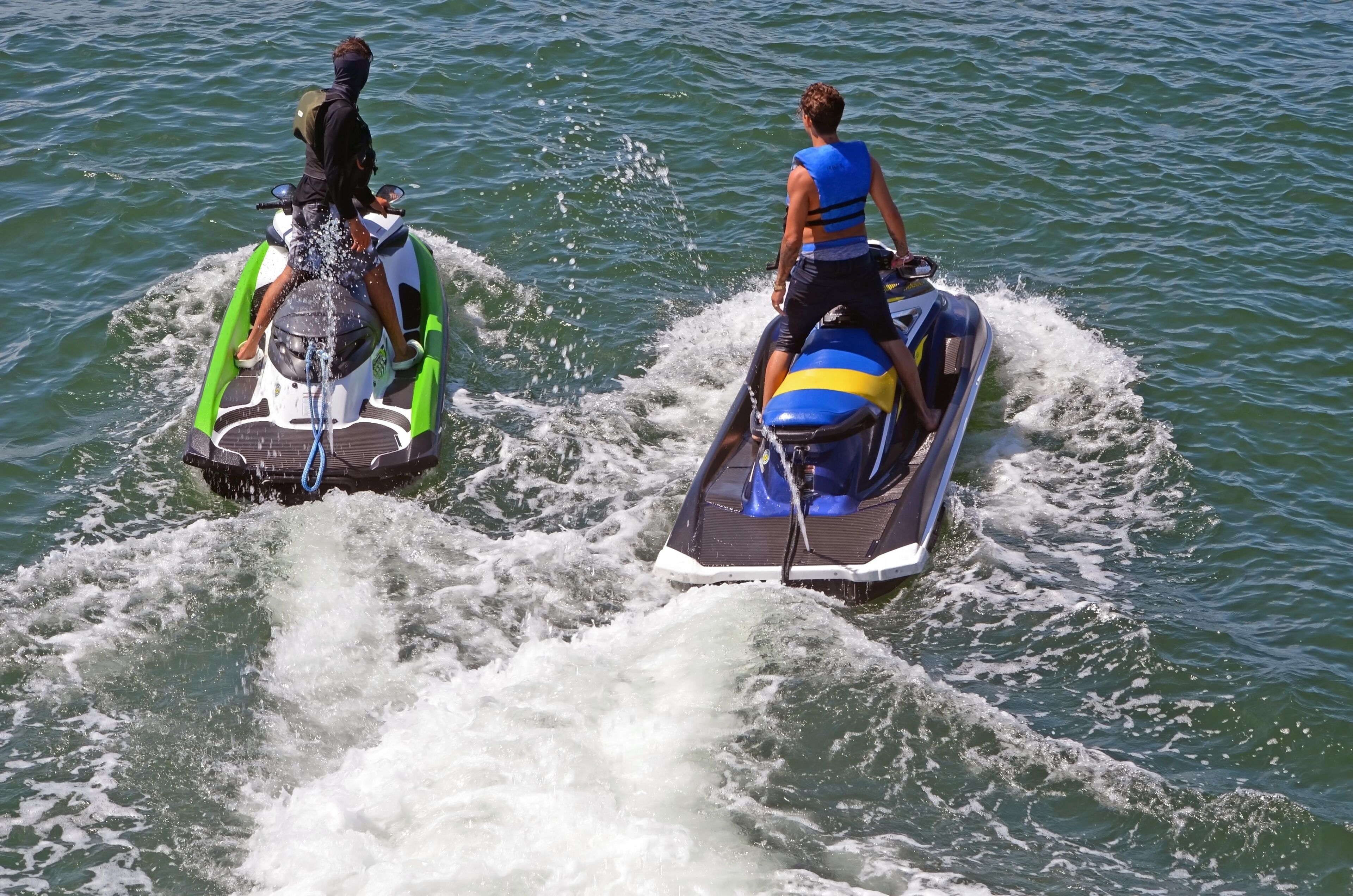 Duas pessoas em jet skis em um corpo de água.