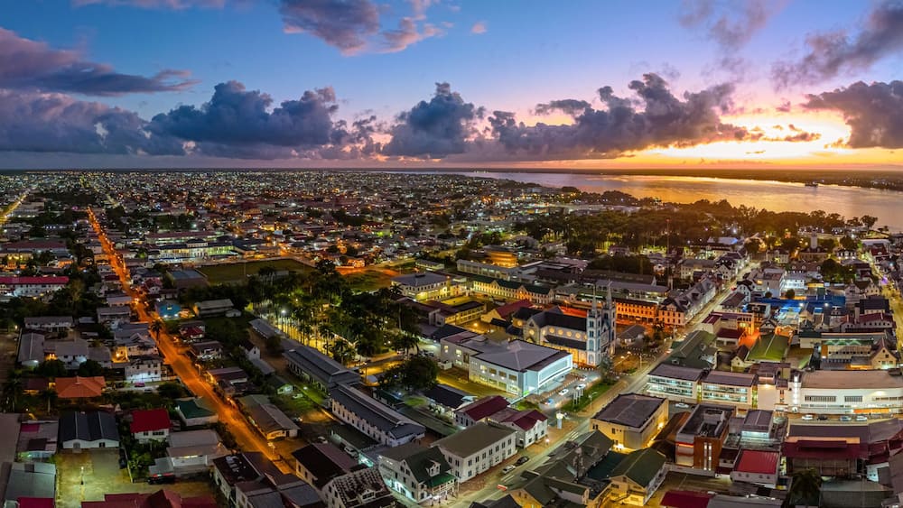 Aerial cityscape of Paramaribo, Suriname, featuring the historic Saint Peter and Paul Cathedral and surrounding colonial architecture bathed in beautiful sunrise light near the riverbank