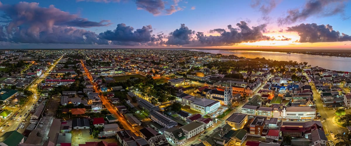 Aerial cityscape of Paramaribo, Suriname, featuring the historic Saint Peter and Paul Cathedral and surrounding colonial architecture bathed in beautiful sunrise light near the riverbank