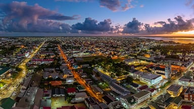 Aerial cityscape of Paramaribo, Suriname, featuring the historic Saint Peter and Paul Cathedral and surrounding colonial architecture bathed in beautiful sunrise light near the riverbank