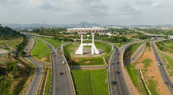 A large white monument with the inscription "YOU ARE WELCOME" in the center of a roundabout, surrounded by green spaces and roads.