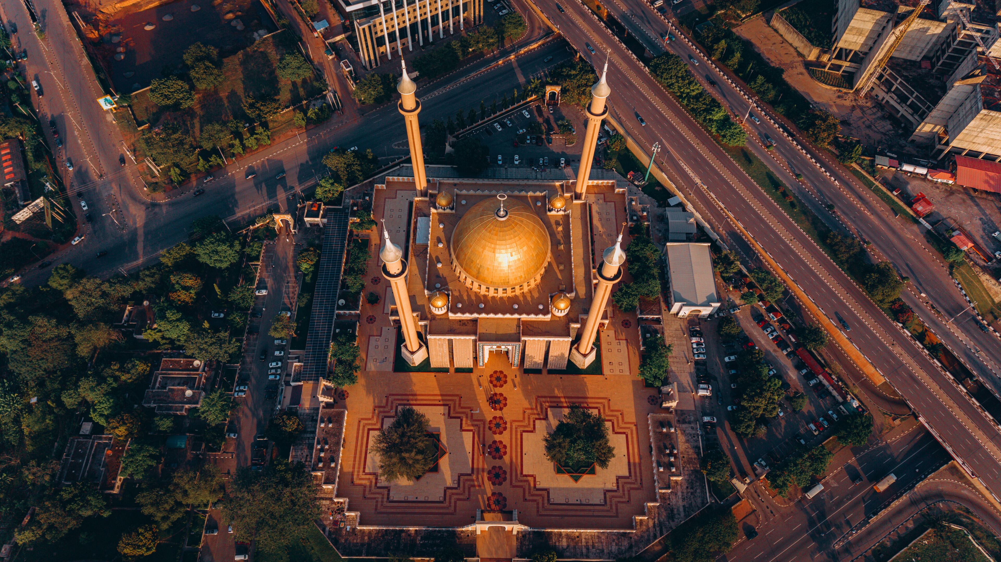 Aerial view of the National Mosque casting long shadows in the golden light, nestled amid the bustling roads and green spaces, Abuja, Federal Capital Territory, Nigeria.