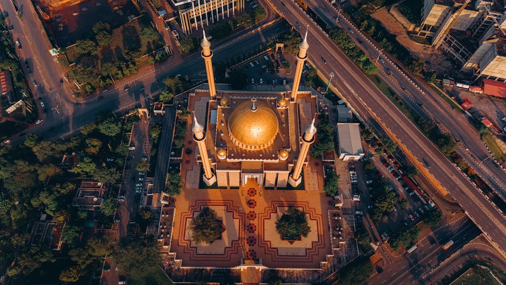 Aerial view of the National Mosque casting long shadows in the golden light, nestled amid the bustling roads and green spaces, Abuja, Federal Capital Territory, Nigeria.