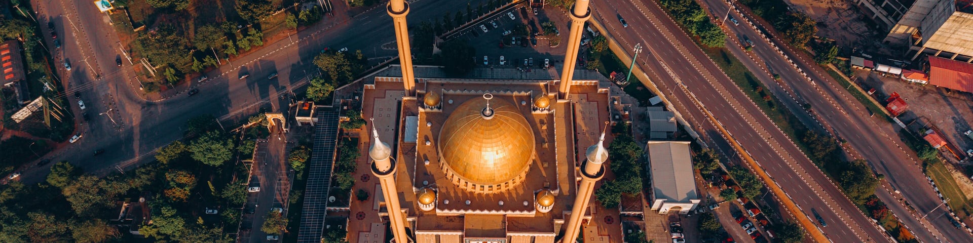 Aerial view of the National Mosque casting long shadows in the golden light, nestled amid the bustling roads and green spaces, Abuja, Federal Capital Territory, Nigeria.