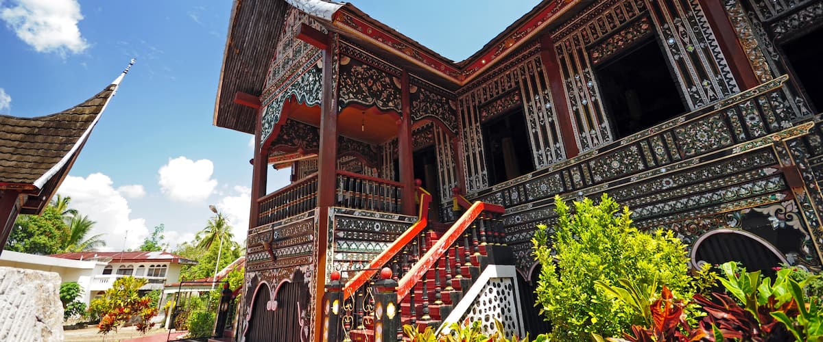 A traditional building with ornate architecture, a staircase, and surrounding greenery.