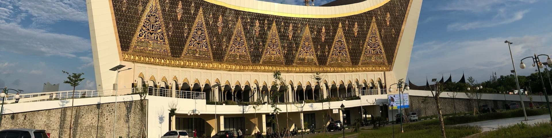 A large, modern building with a curved roof and intricate golden patterns.