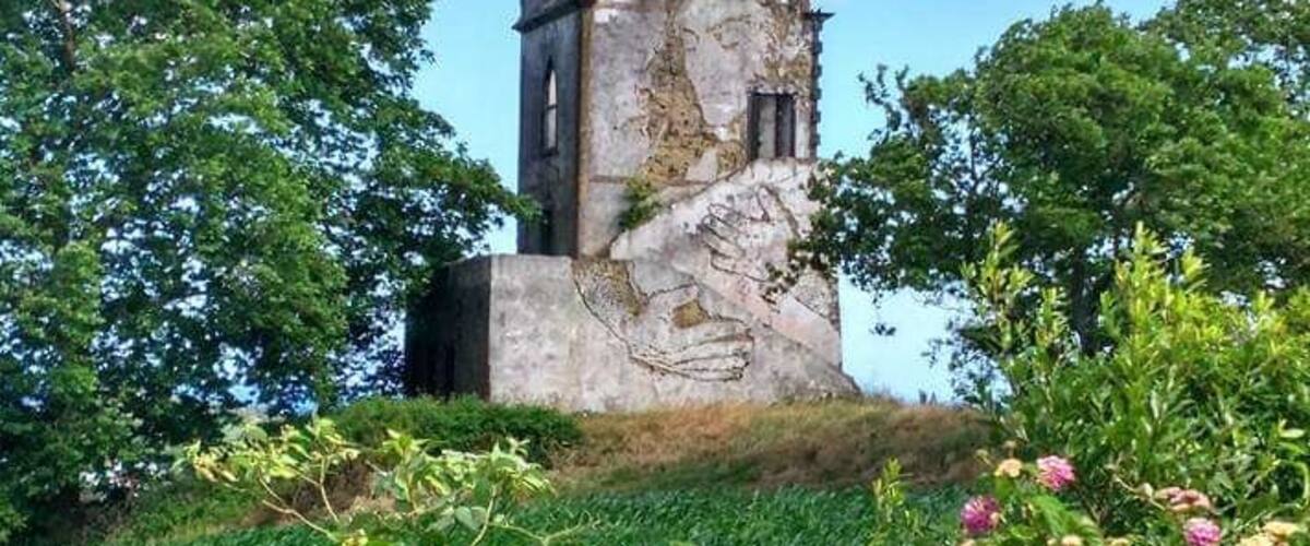 A historic stone tower surrounded by lush greenery and vibrant flowers.