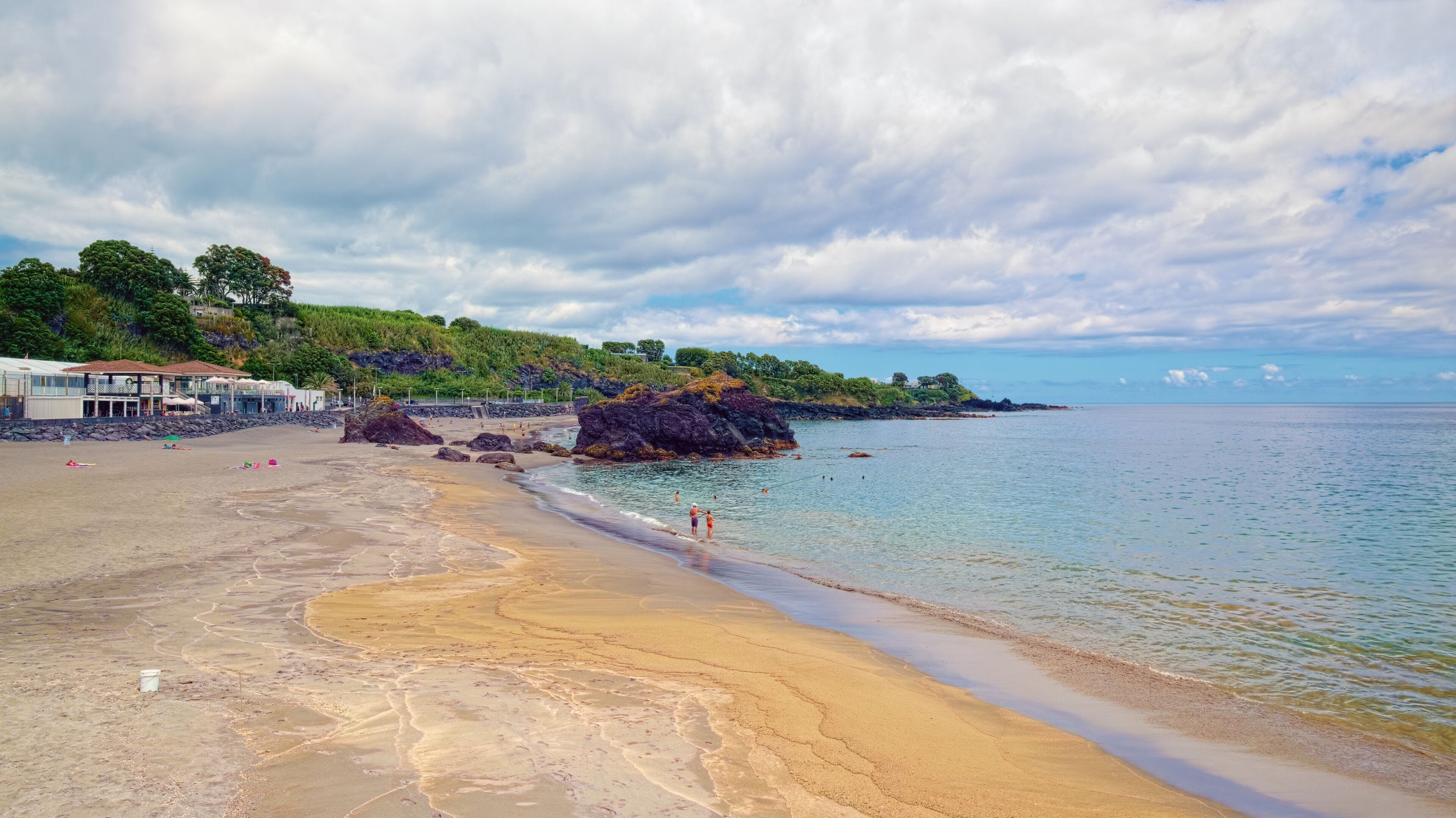 Sandy beach with black volcanic rocks at coast near the Vila Franca do Campo town, located on Sao Miguel island of Azores, Portugal.