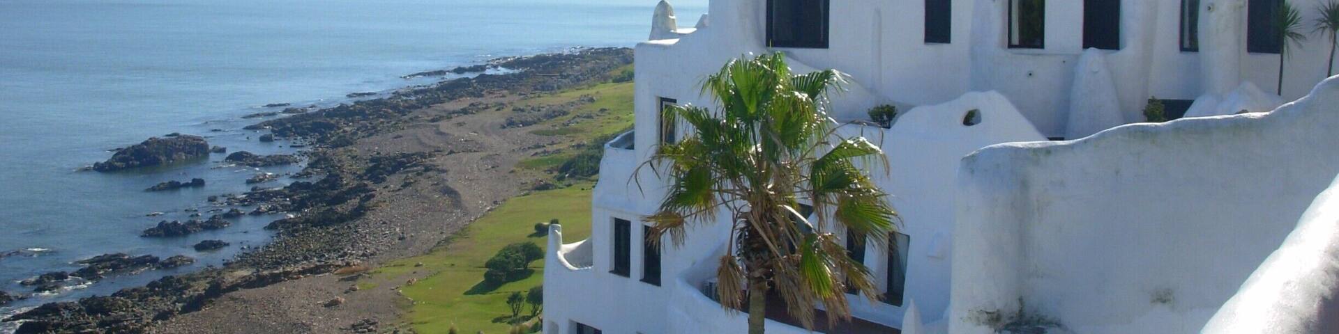 A coastal building with a white facade and multiple windows overlooking the sea.
