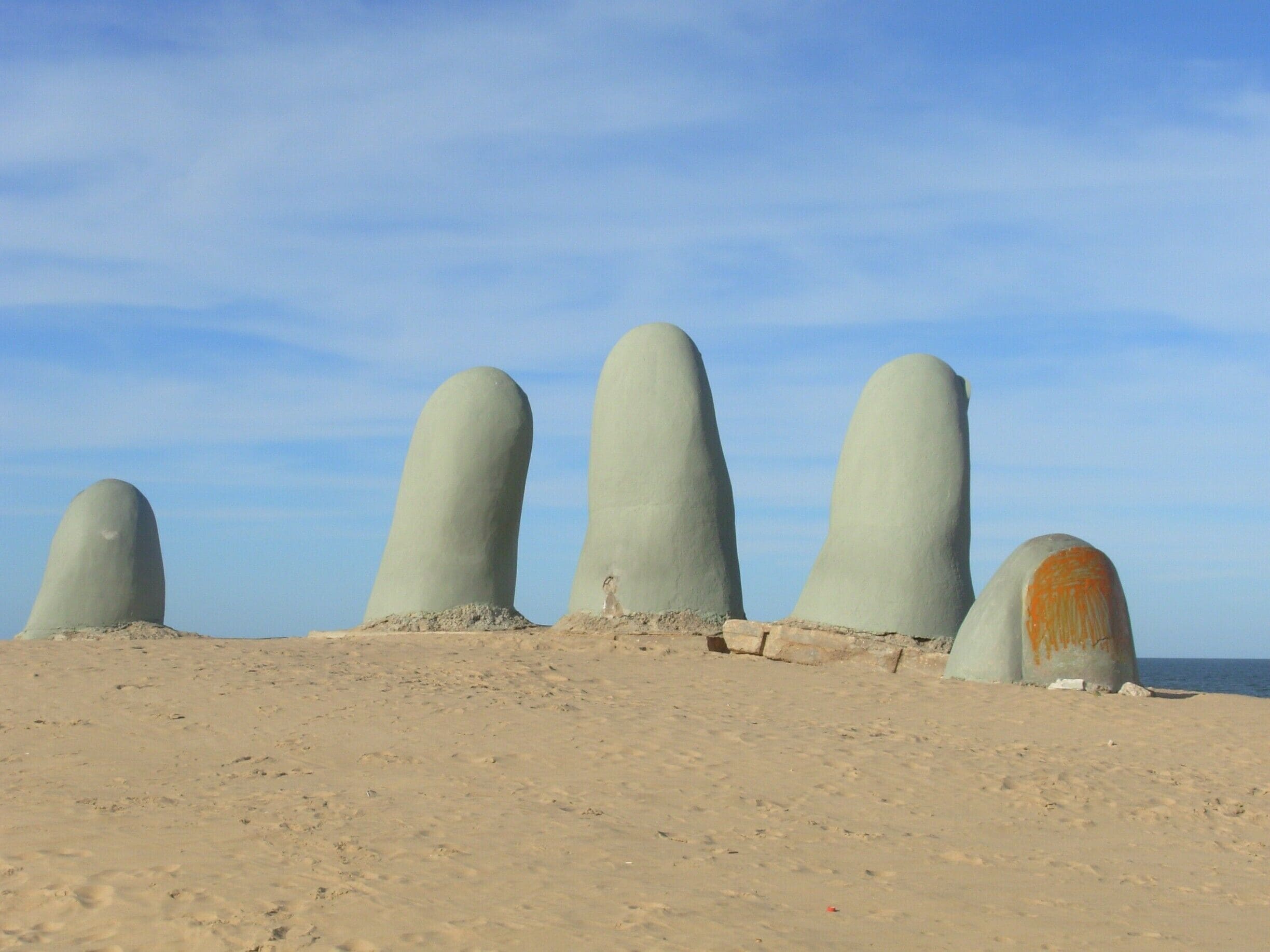 Uma praia arenosa com cinco grandes estruturas cônicas e lisas.