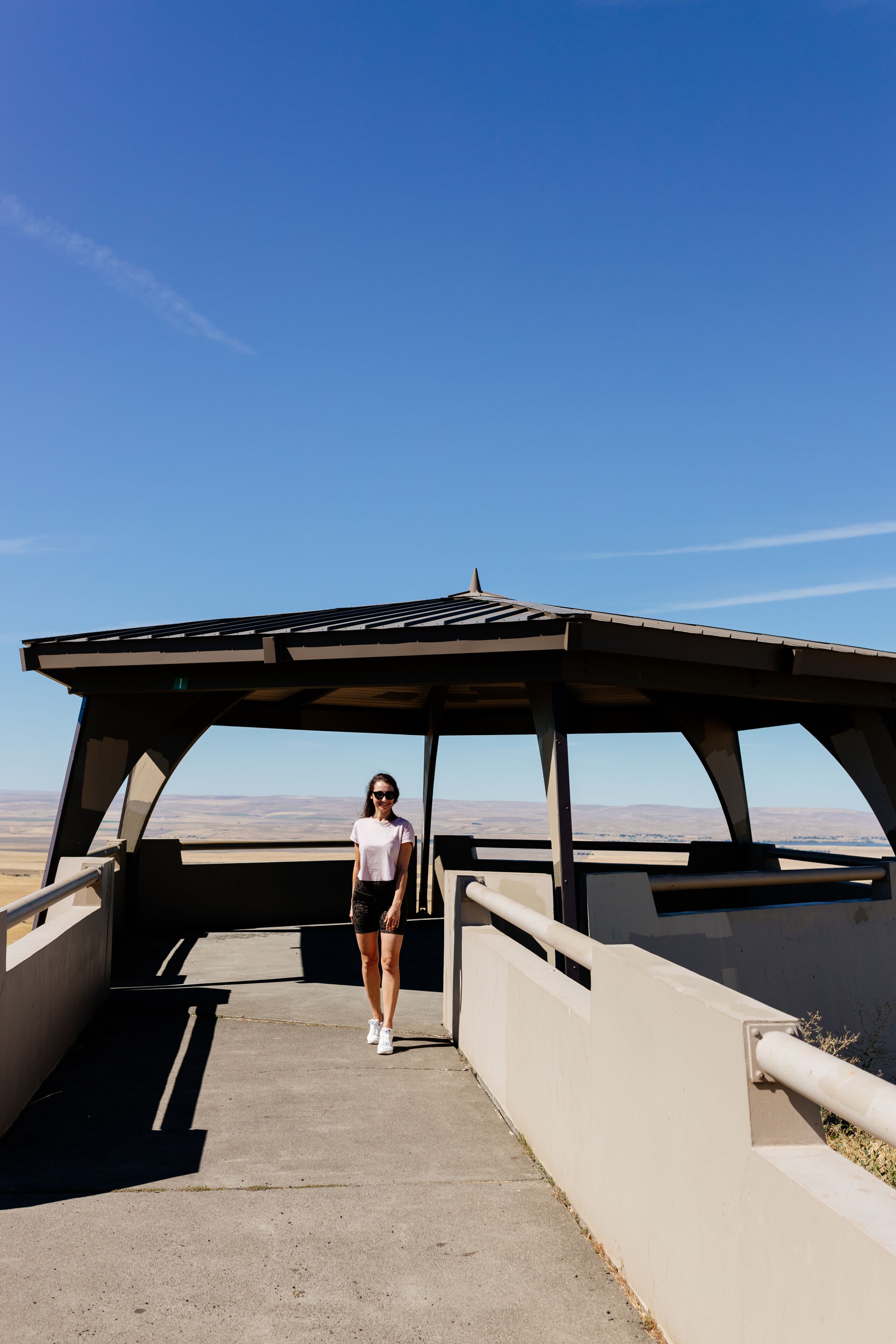 A person standing under a shelter with a clear blue sky in the background.