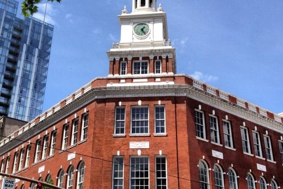 Um edifício histórico de tijolos vermelhos com uma torre do relógio, janelas grandes e uma placa com o nome One Way Cafe.