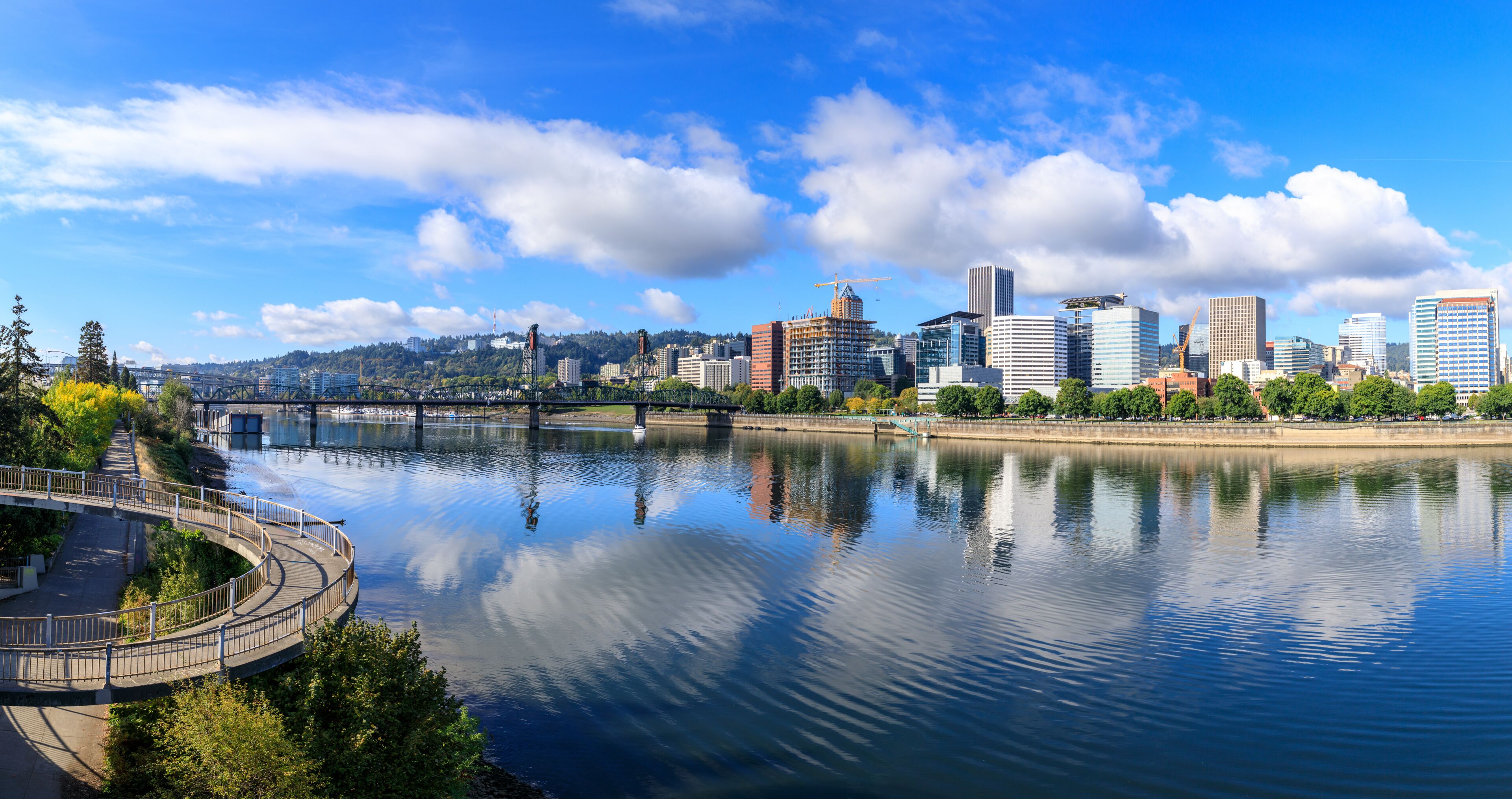 A river with a bridge, a city skyline, and a clear blue sky.