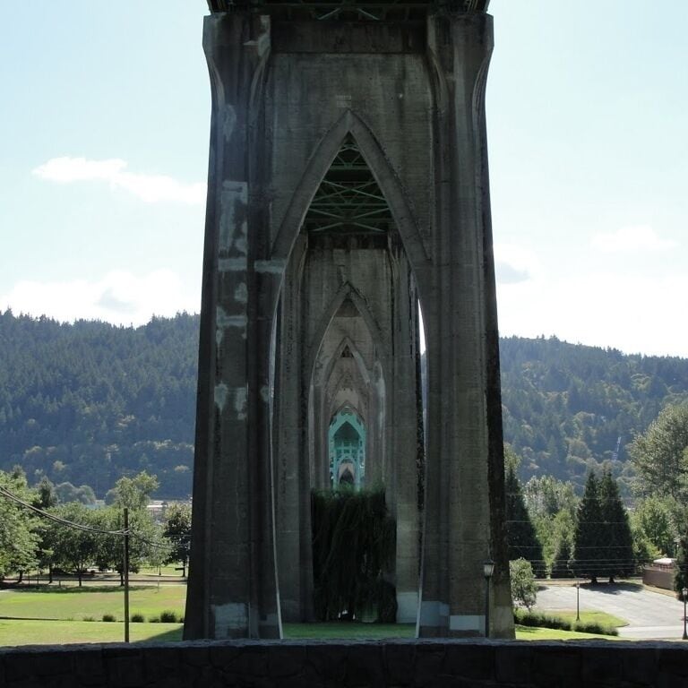 A beautiful park that uses the supports of the gothic styled St John's bridge to echo the arched interior of a medieval cathedral.  The park includes benches, a small stage and a beach with fishing pier.