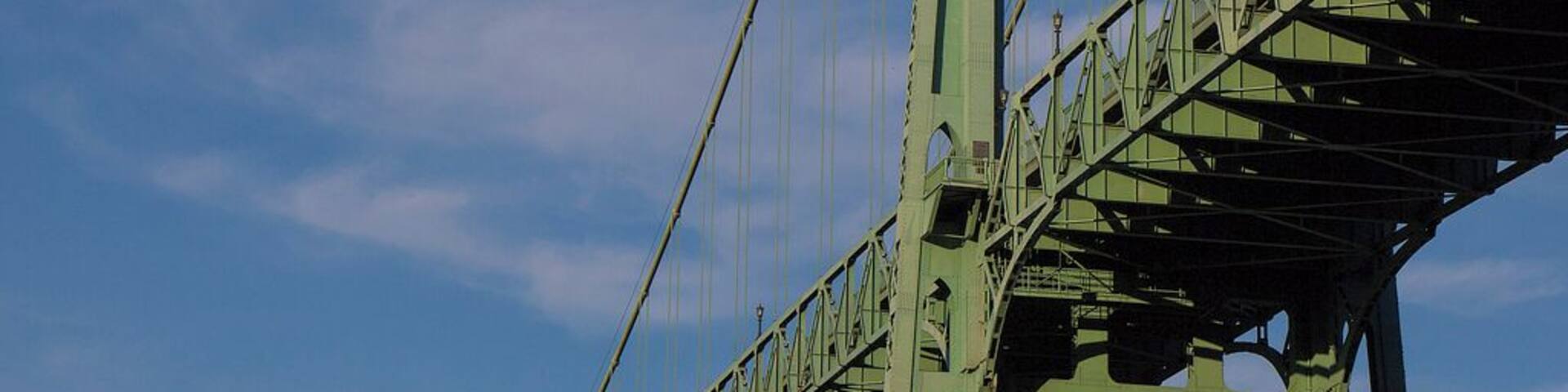 A large green bridge with multiple arches and cables.