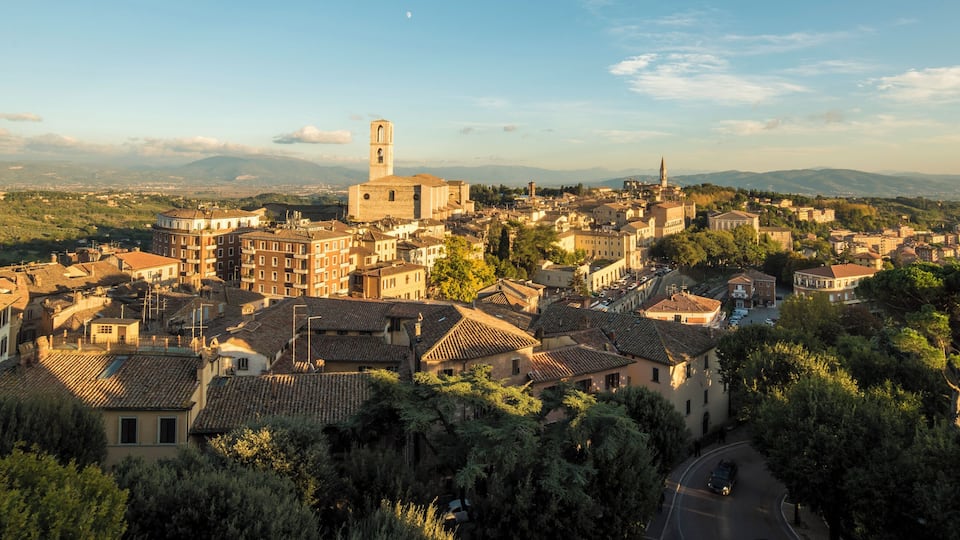 A historic town with a prominent church tower, surrounded by terraced houses and lush greenery.
