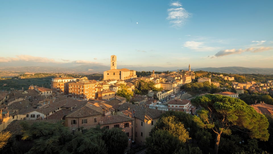 A panoramic view of a historic town with a prominent church tower, cobblestone streets, and surrounding greenery.