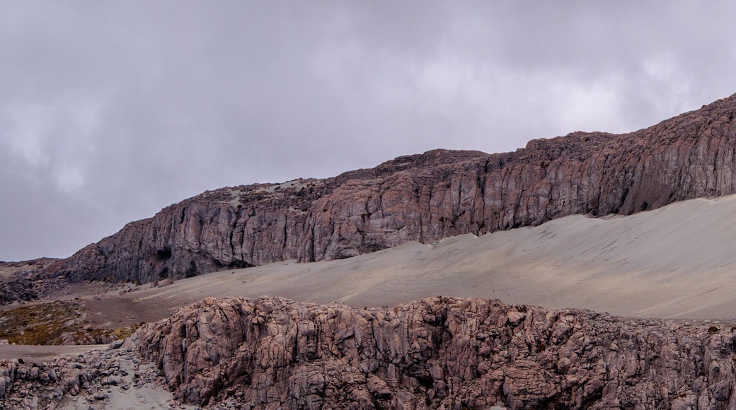 Panorámica de duna de ceniza volcánica blanca sobre pared de roca sedimentaria fracturada en el Parque Nacional Natural Los Nevados, Colombia. Contraste de texturas. Paisaje geológico, vasto y dramáti