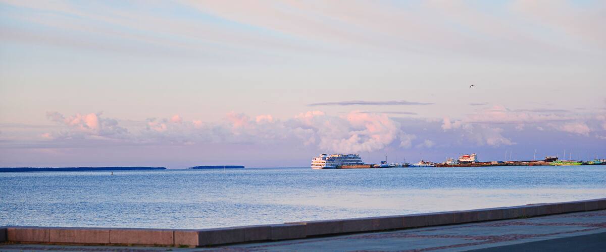 A calm sea with a cruise ship and several smaller boats near the shore.