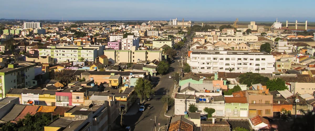 A densely populated urban area with various buildings, roads, and a distant view of the sea.