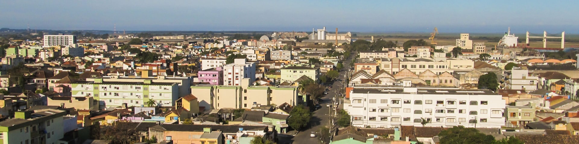 A densely populated urban area with various buildings, roads, and a distant view of the sea.