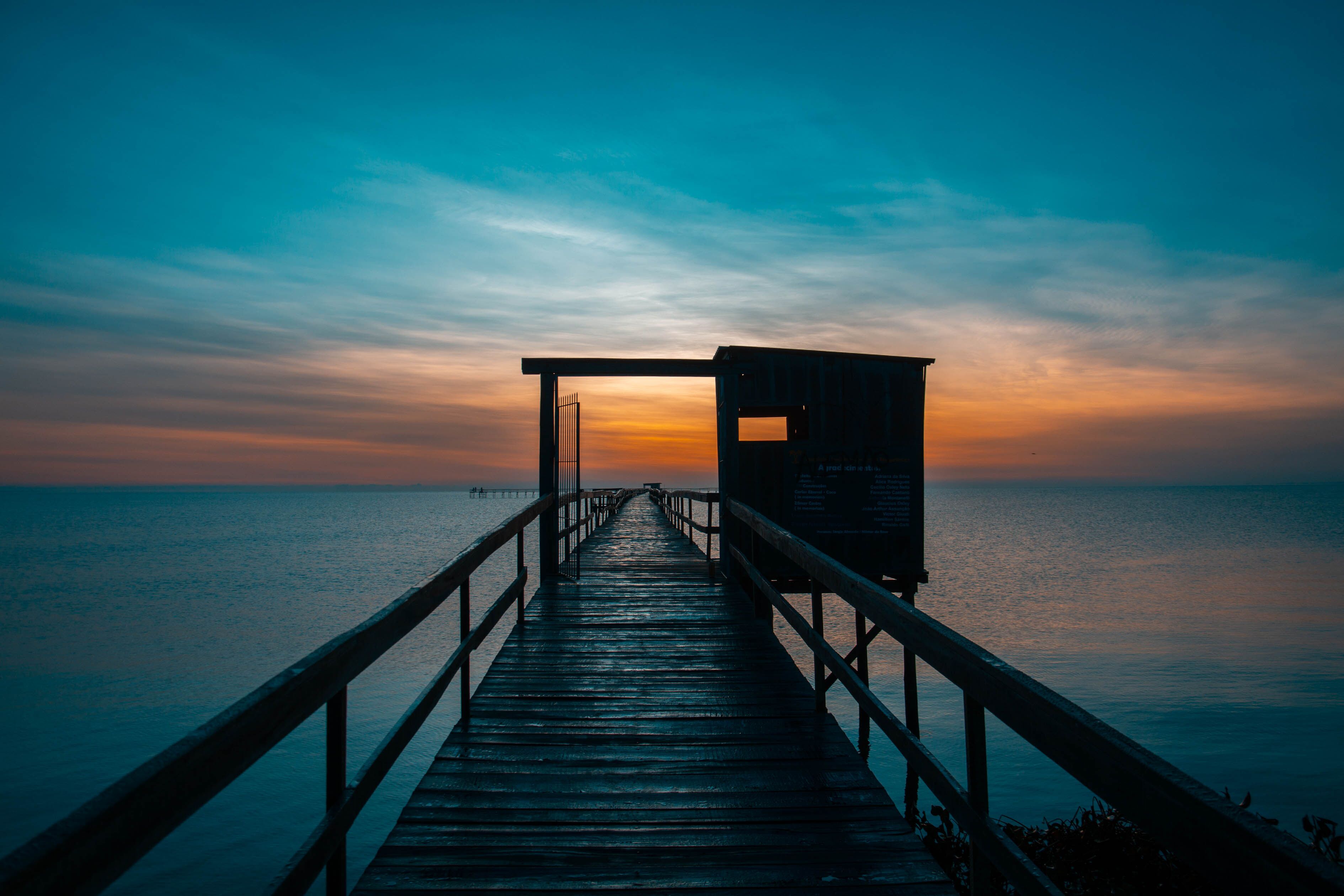 A wooden pier extending into calm waters at sunset.